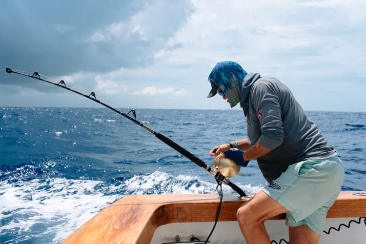 An image of an angler reeling in a fish on an ocean fox fishing charter bahamas.